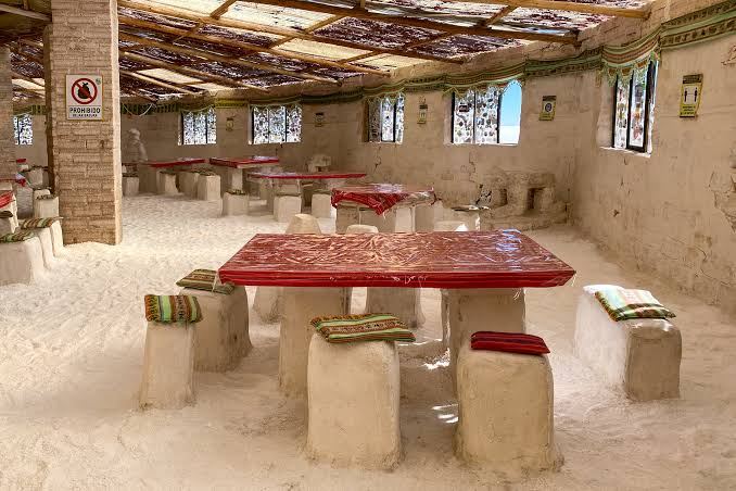 Salle à manger d’un hôtel de sel, avec tables, bancs et murs en blocs de sel