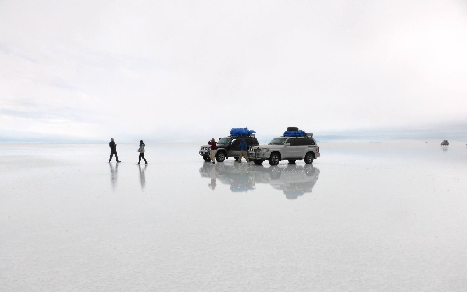 Dos 4×4 sobre el salar cubierto de agua, con efecto espejo